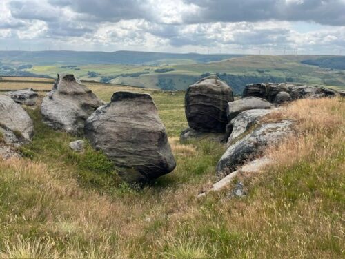 Weathered boulders at the Bridestones with moorland views towards the hills beyond