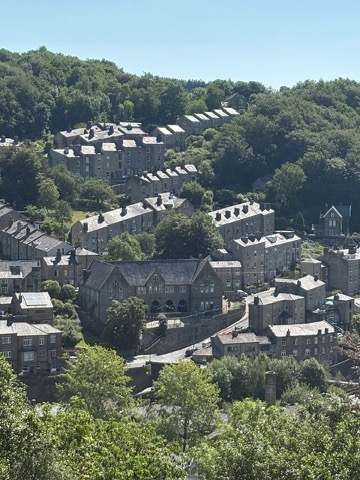 Stone terraced houses stacked on the wooded hillside above Hebden Bridge in West Yorkshire